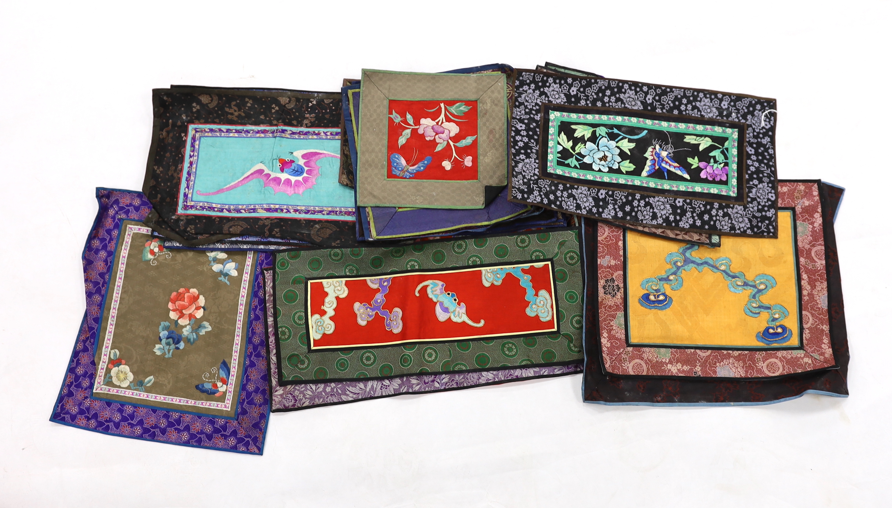 Twenty six assorted Chinese polychrome silk embroidered mats with silk damask borders of varying sizes